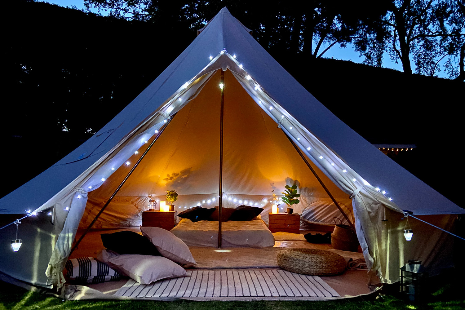 Bell tent lit up at night with beds made inside