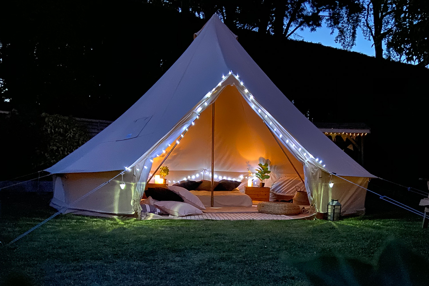 Bell tent glowing at dusk, beds made up inside