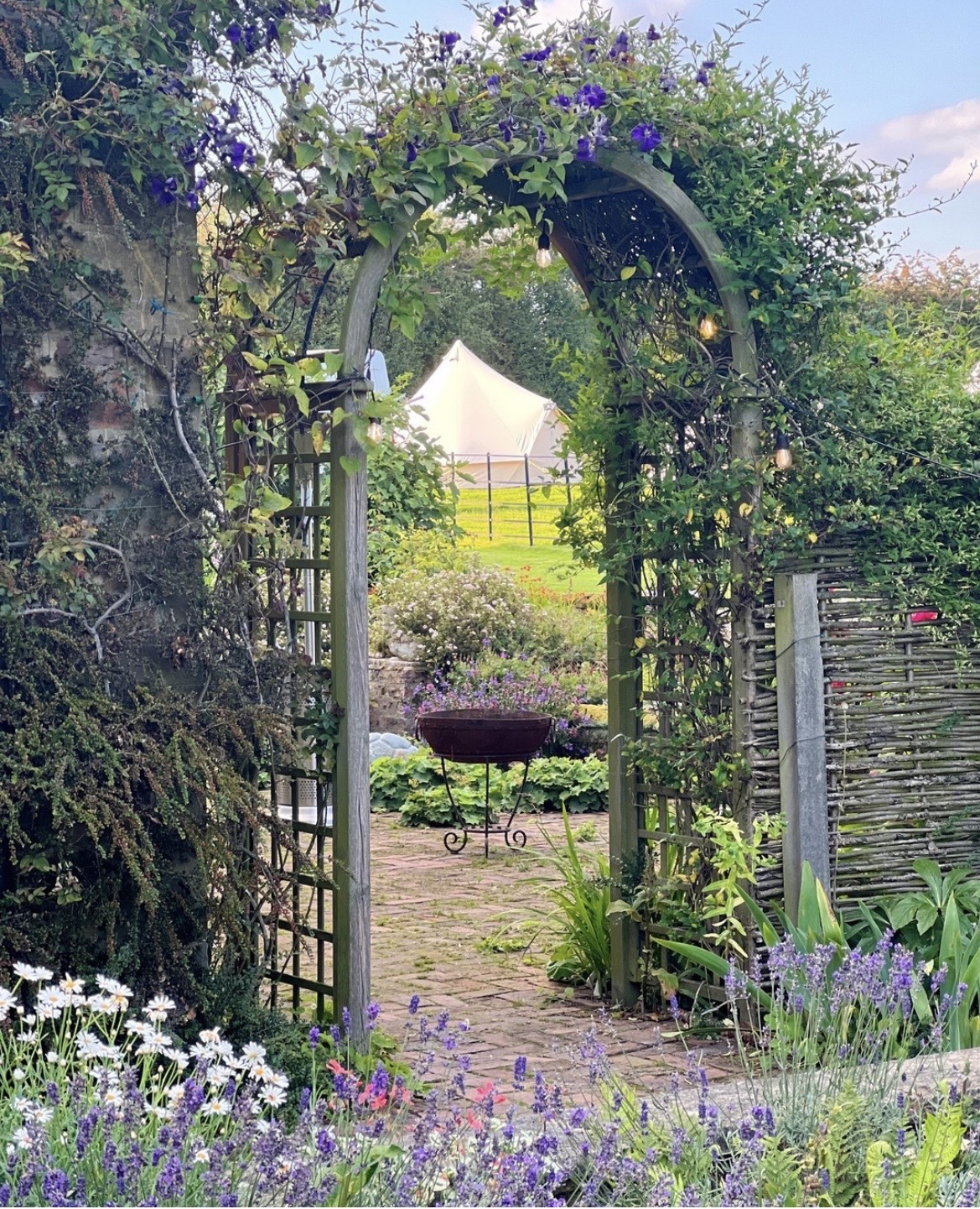 Garden archway with lavender, bell tent beyond